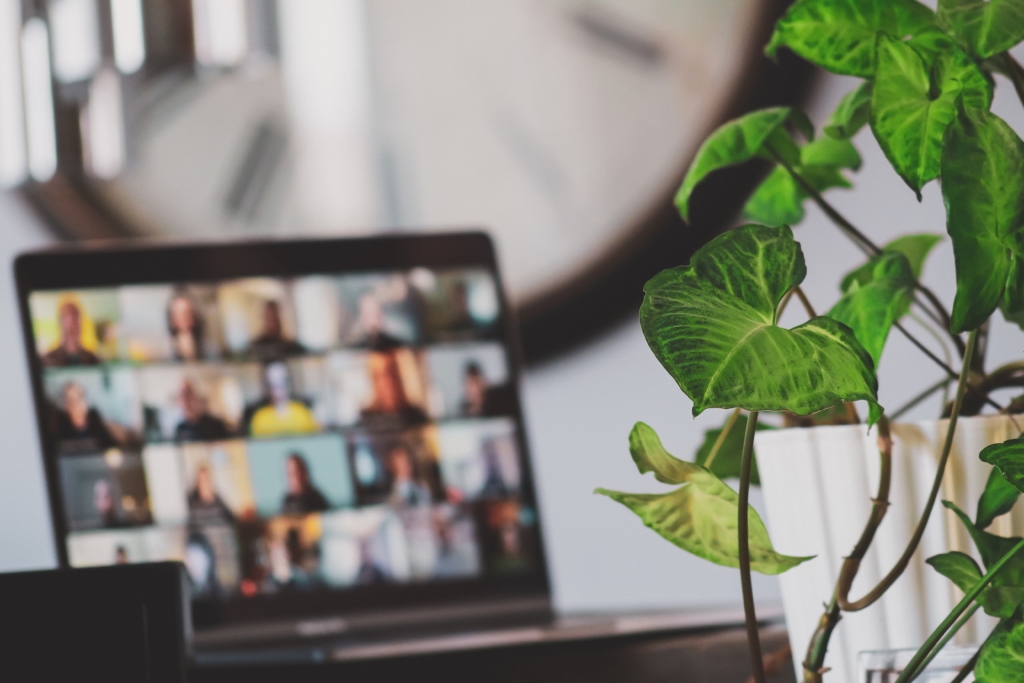 Photo of a laptop screen in a room participating in a remote meeting
