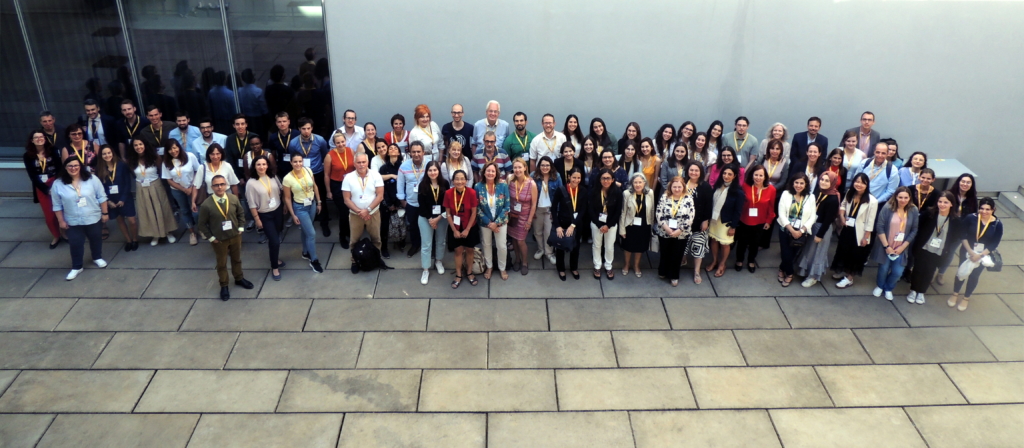 Group photo of 100+ people taken outside in a courtyard. Photo is taken from above to fit all into the composition.