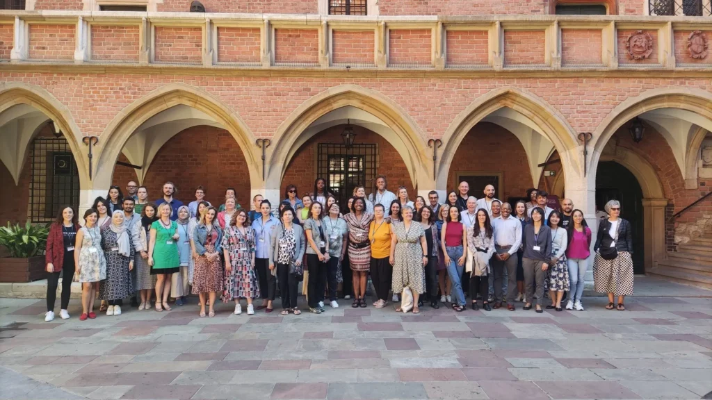 Group photo of 60 plus people standing for a group photo outside in the summer