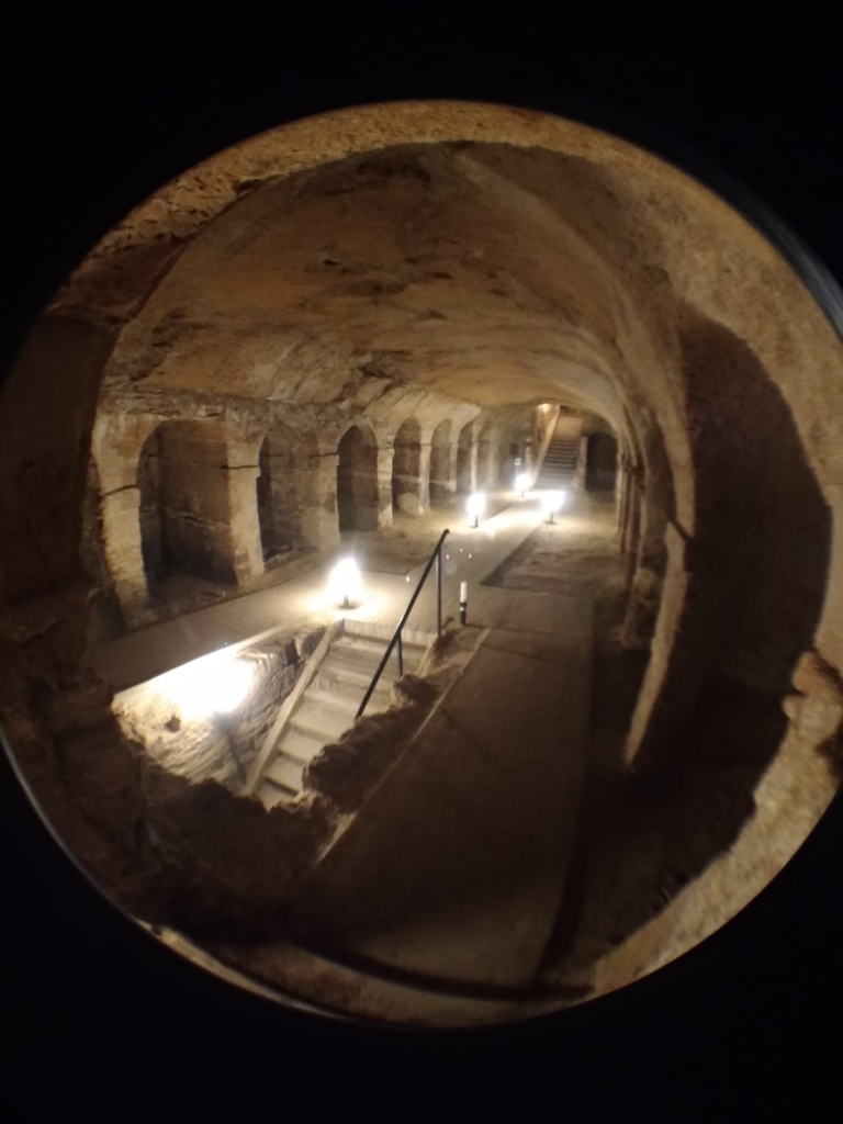 Underground-photo of a dark underground tunnel with columns and a staircase