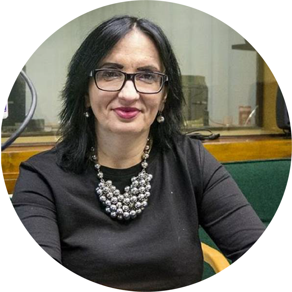 photo of a woman with brown hair, wearing glasses and a shiny necklace