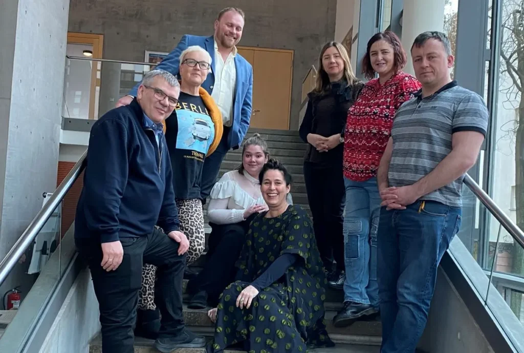 a group of 8 people standing and sitting on the stairs