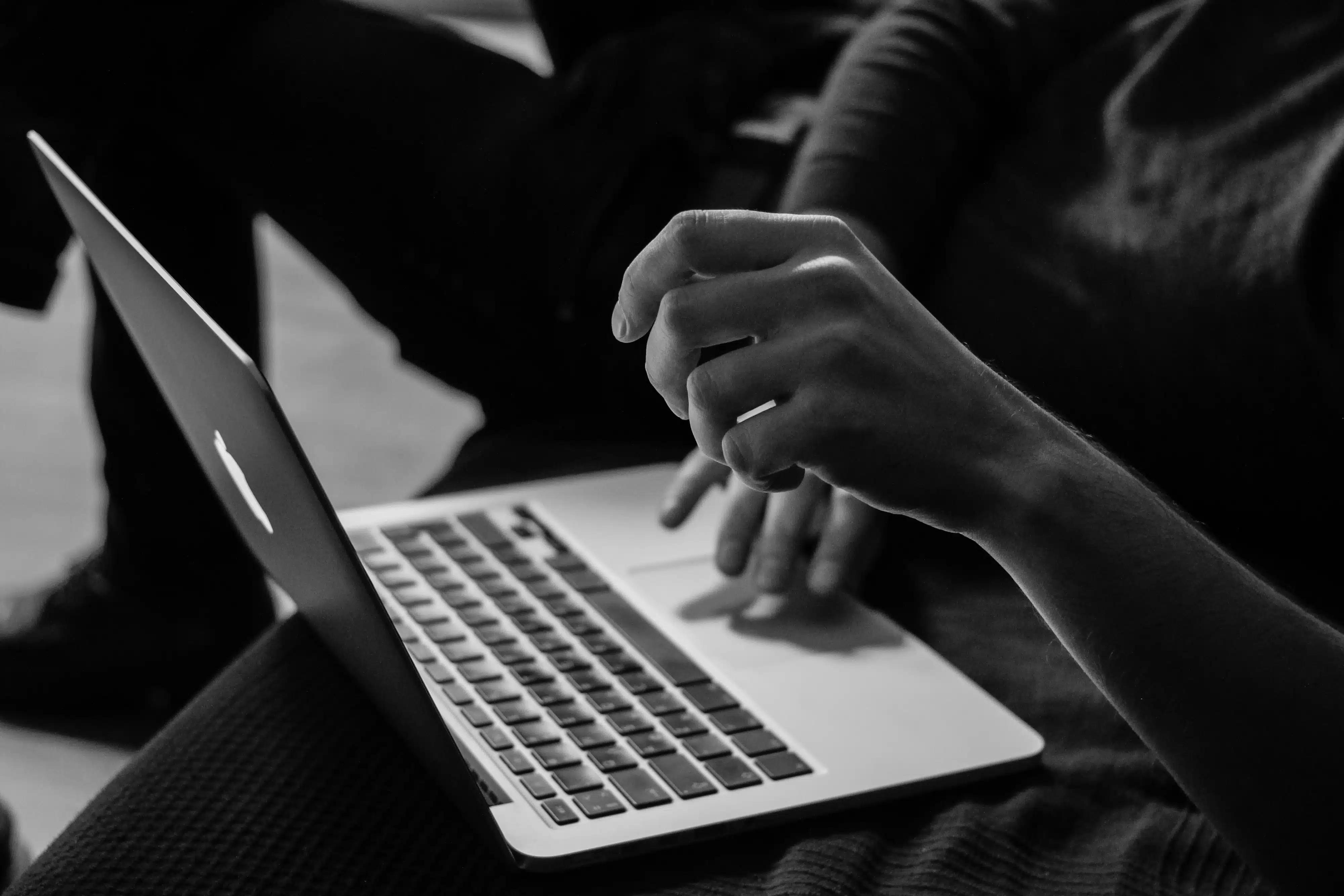 A black and white photo of someone working on a laptop computer